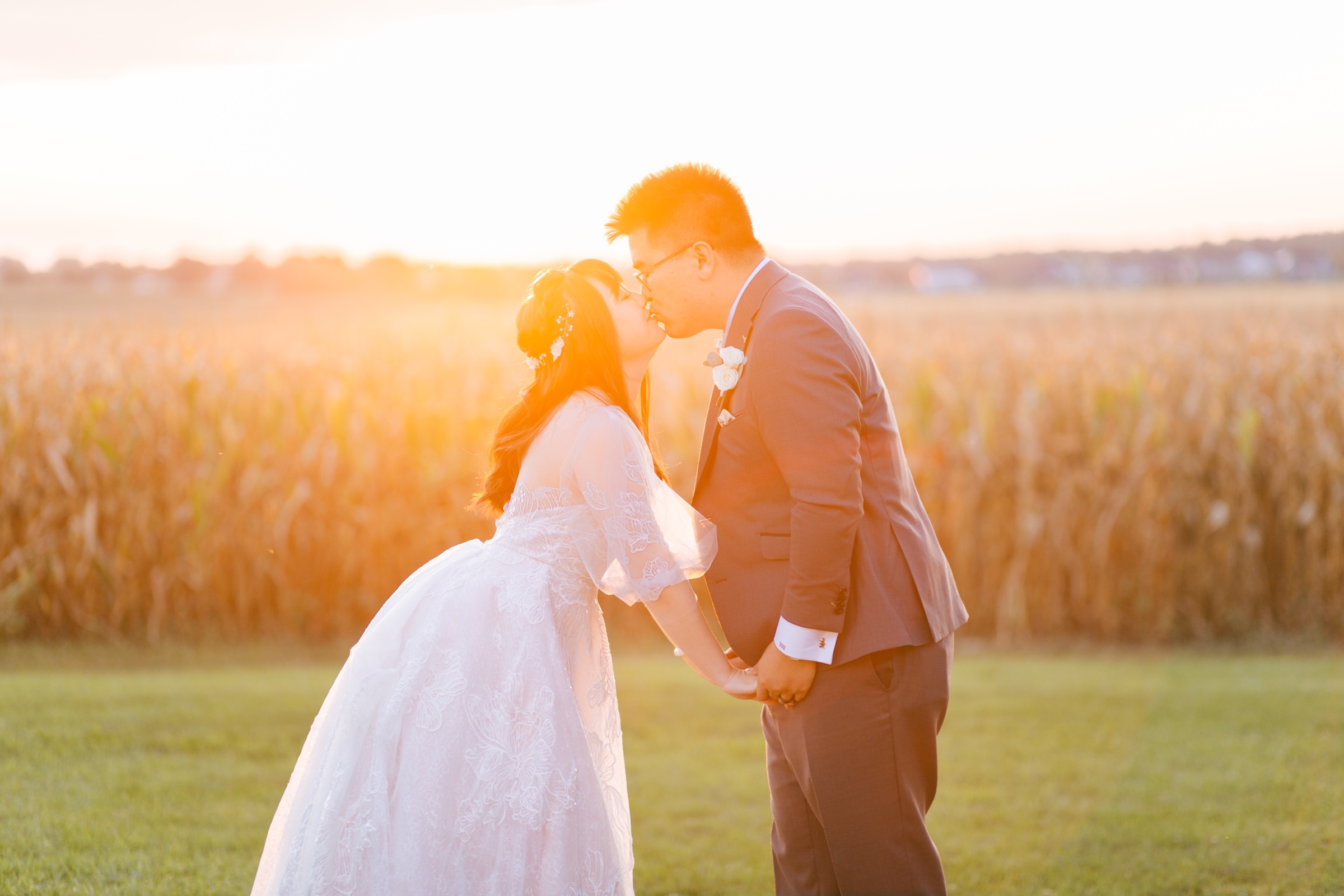 Newlyweds kissing in glowing sunset light