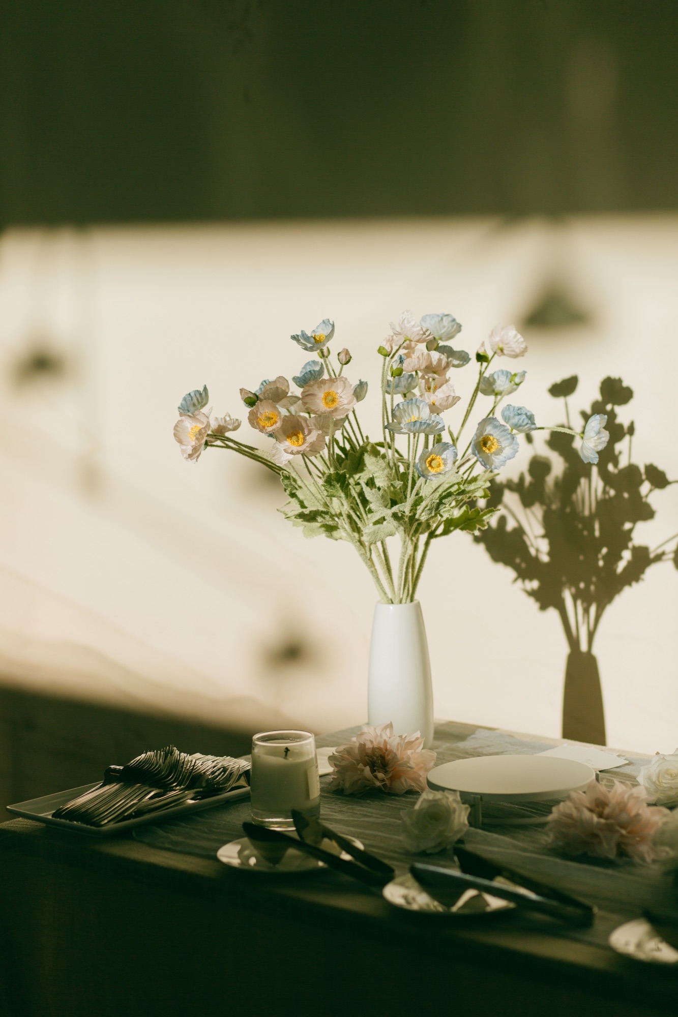 Blue and white flowers casting shadows across a table