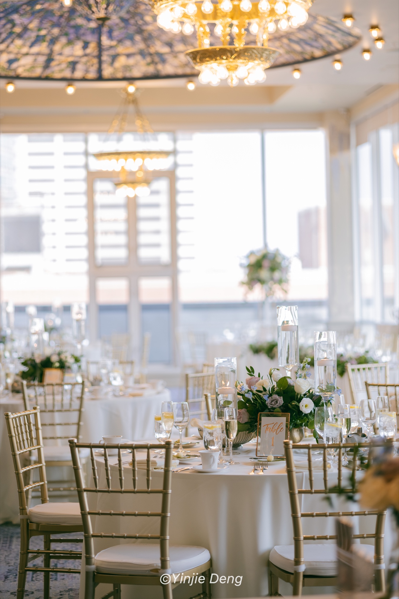 A reception table with flowers, candles, glassware, and chandeliers
