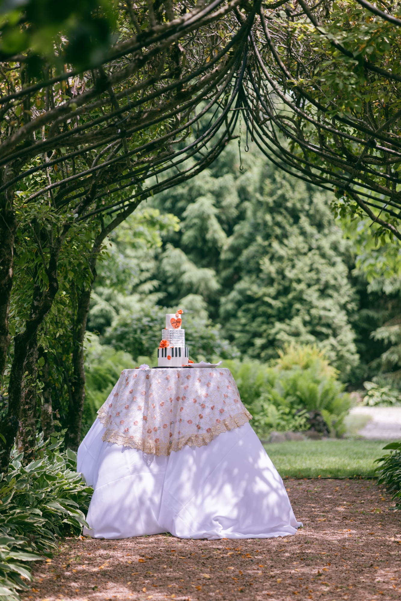 A wedding cake beneath a leafy garden arbor