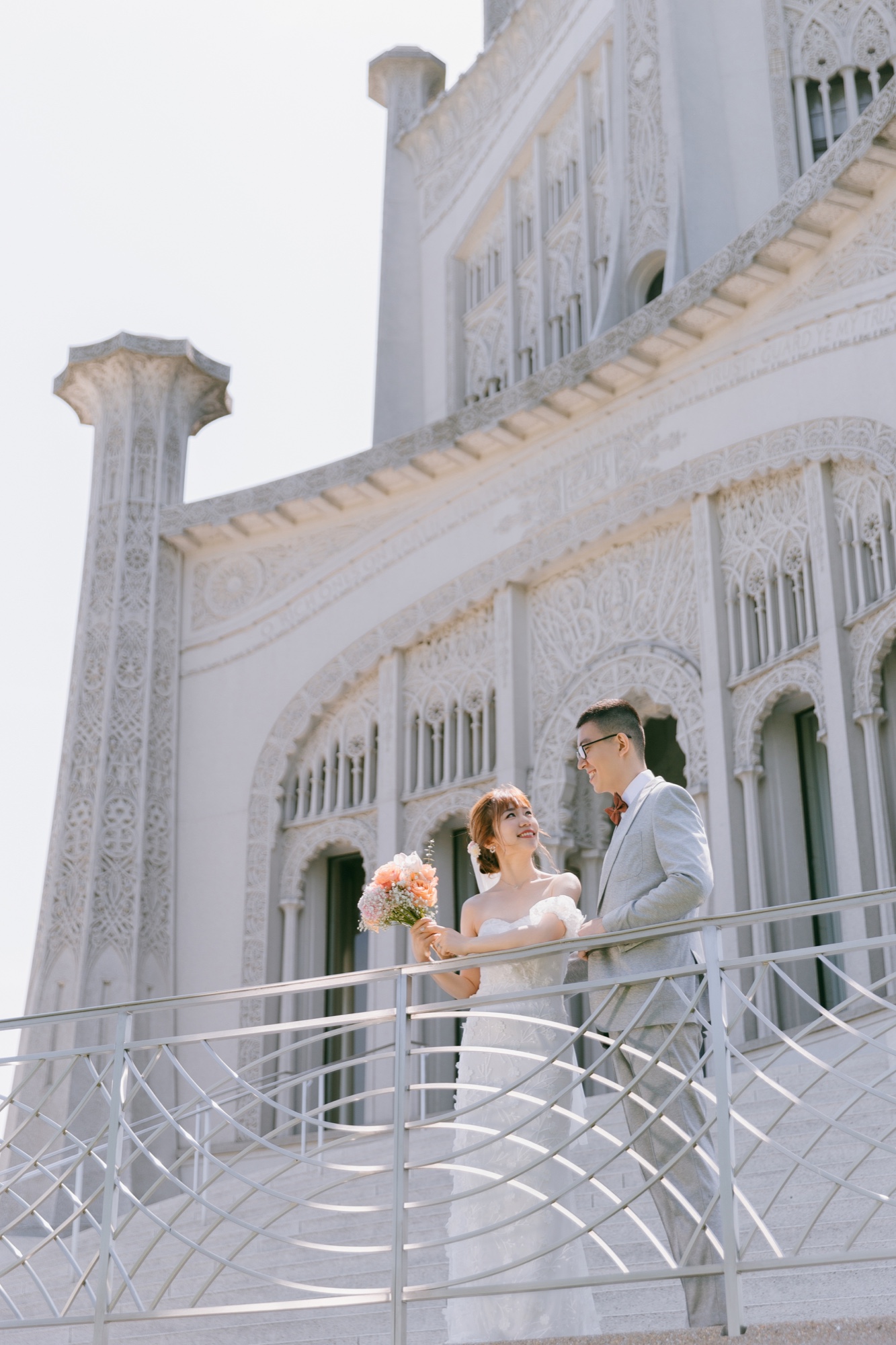 A couple standing on the balcony of an ornate stone building