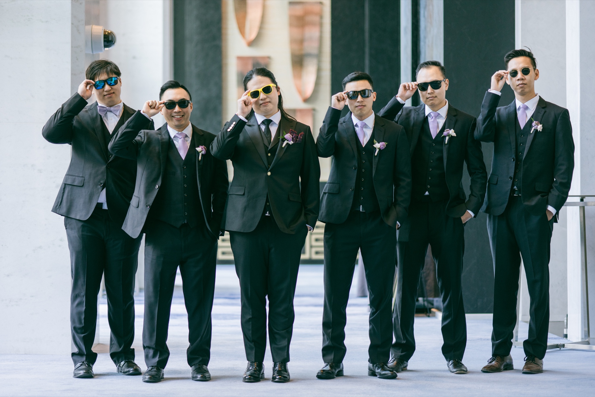 A wedding party in dark suits posing with sunglasses