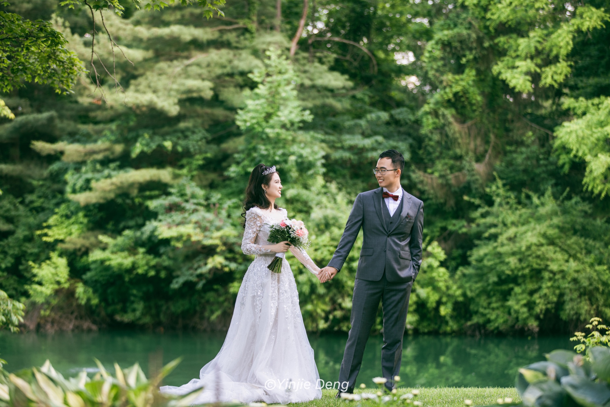 Newlyweds holding hands beside a garden pond