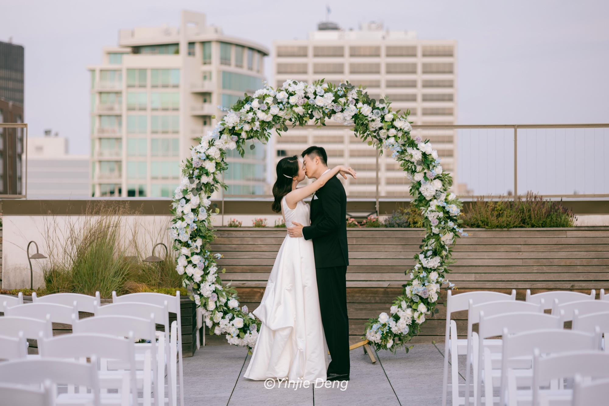 Newlyweds kissing beneath a circular floral arch