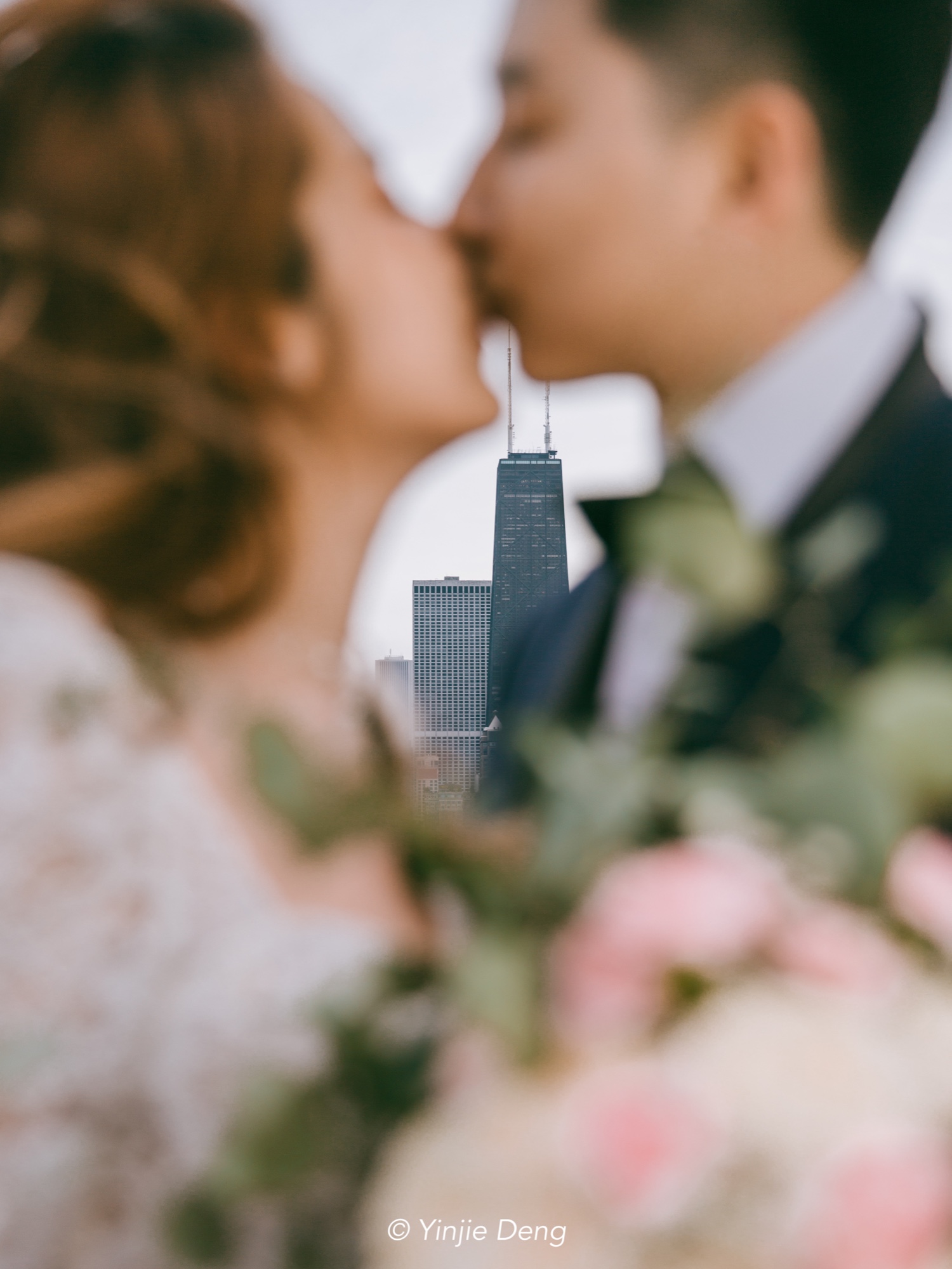 A softly blurred couple kissing with the Chicago skyline between them