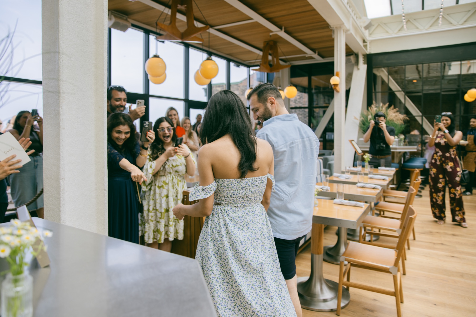 A couple entering a restaurant while friends react around them