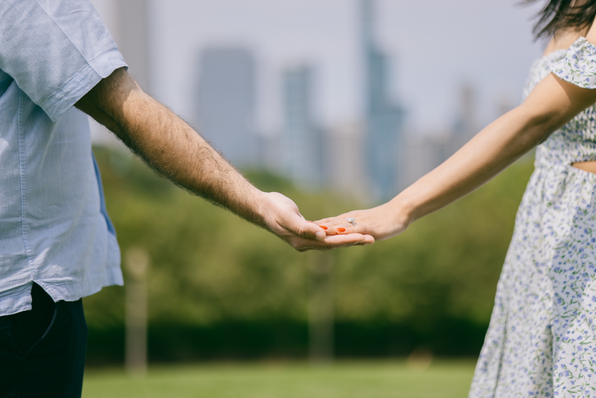 A close view of a couple holding hands and an engagement ring